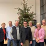 Personengruppe vor einem Weihnachtsbaum